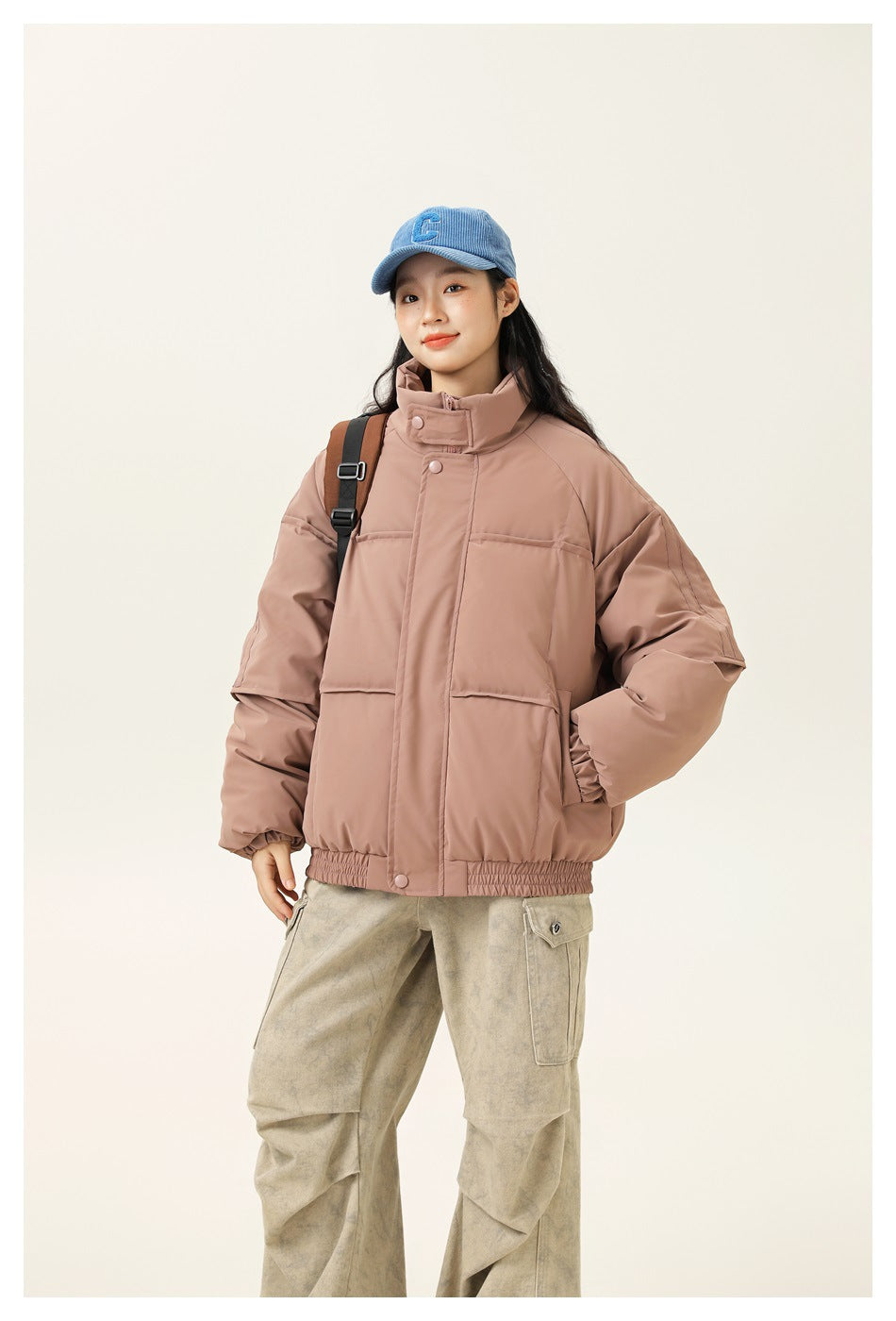 Woman models a dusty rose oversized jacket with a high stand collar, snap closure, and large front pockets.