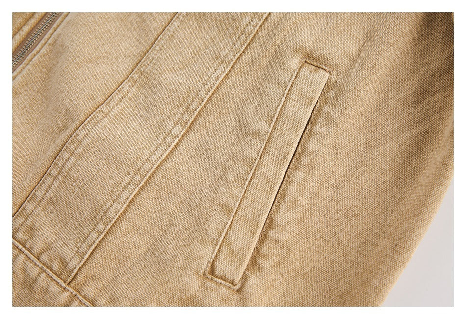 Close-up of a narrow welt pocket on tan jacket fabric, with part of a zipper visible at the edge.