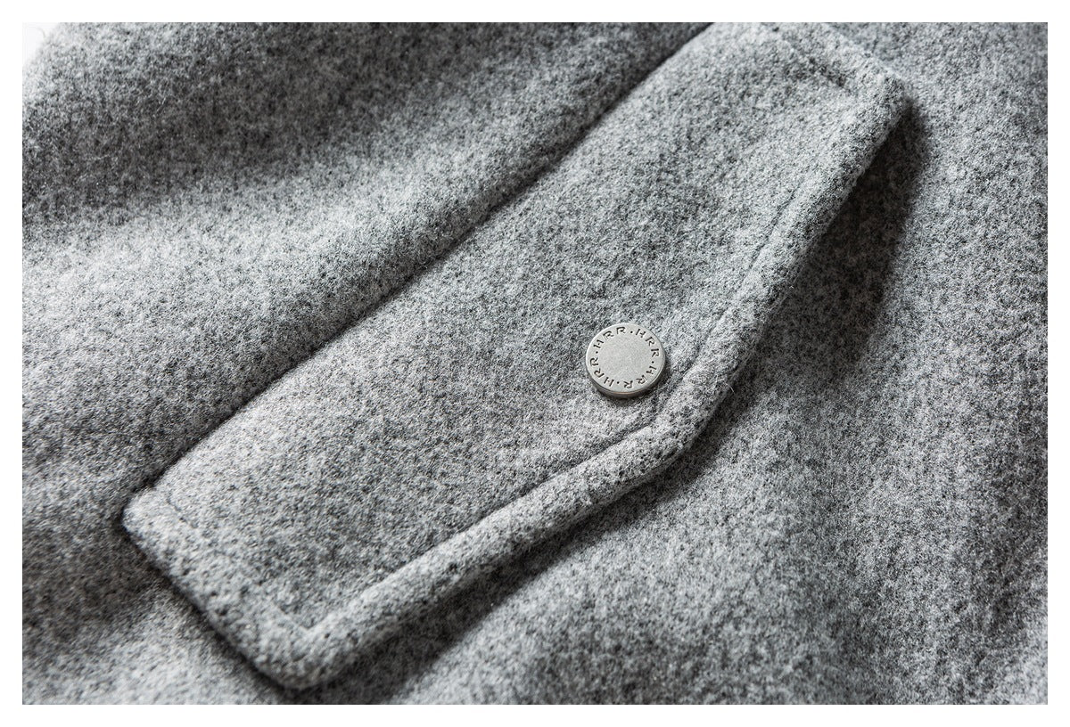 Close-up of a gray coat pocket flap with a round metal button.