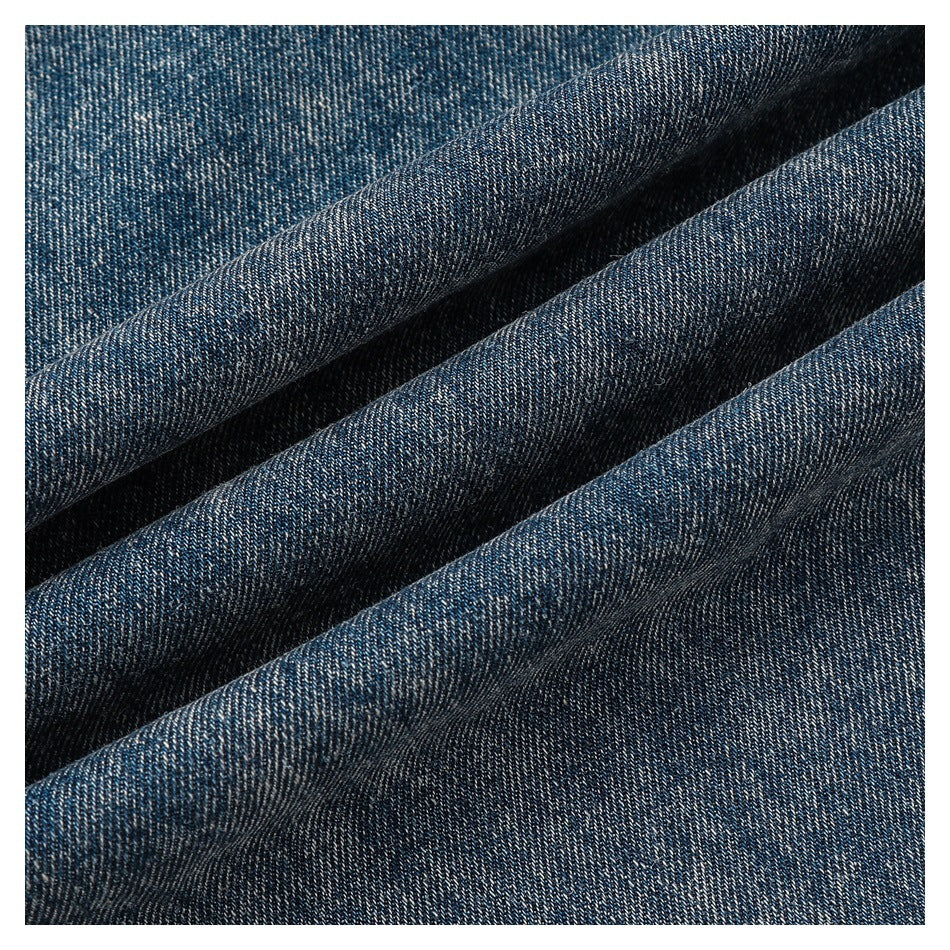 Close-up of dark blue denim-like fabric folded to show its diagonal twill texture.
