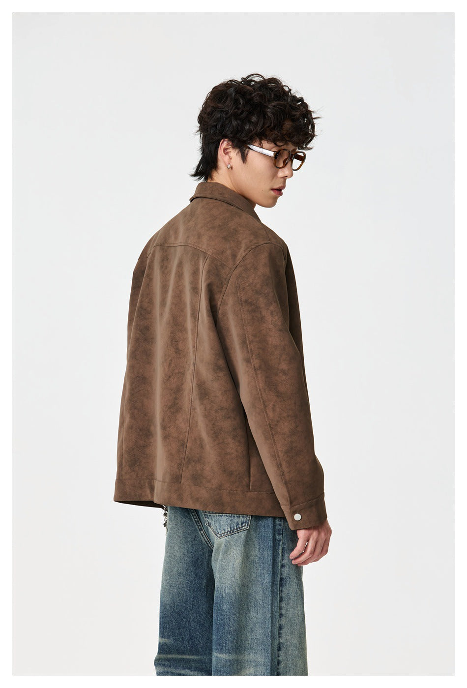 Back view of a model wearing a brown jacket with a shoulder yoke seam and blue jeans.