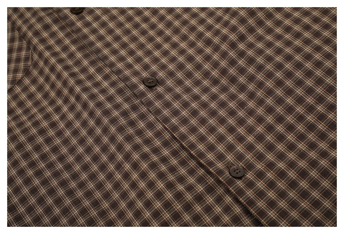 Close-up of the brown plaid shirt's button placket and dark buttons.