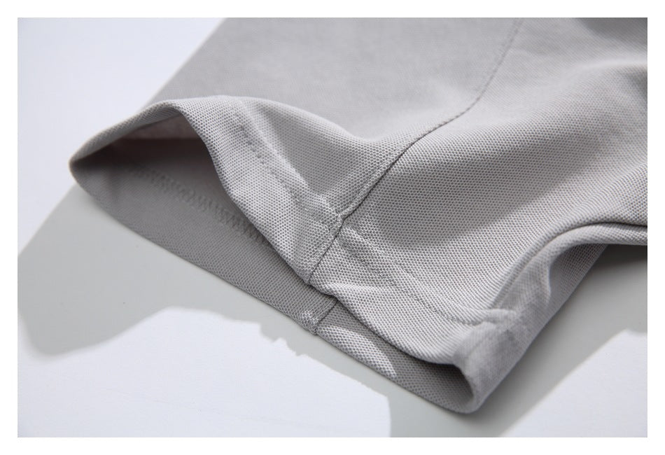 Close-up of the light gray T-shirt's sleeve hem, stitching, and textured fabric surface.