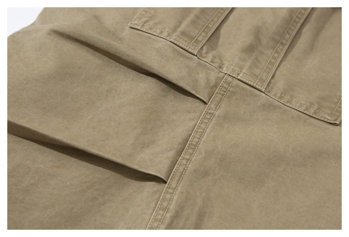 Close-up of khaki trouser fabric and double-stitched seams around a cargo pocket.