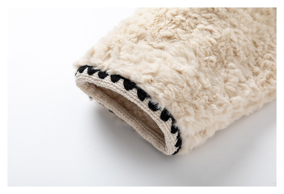 Close-up of a cream fluffy garment cuff with a beige knit edge and black loop trim.
