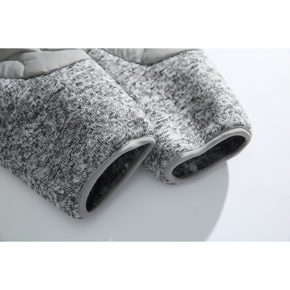Close-up of two mottled gray knit jacket cuffs with gray edge binding.