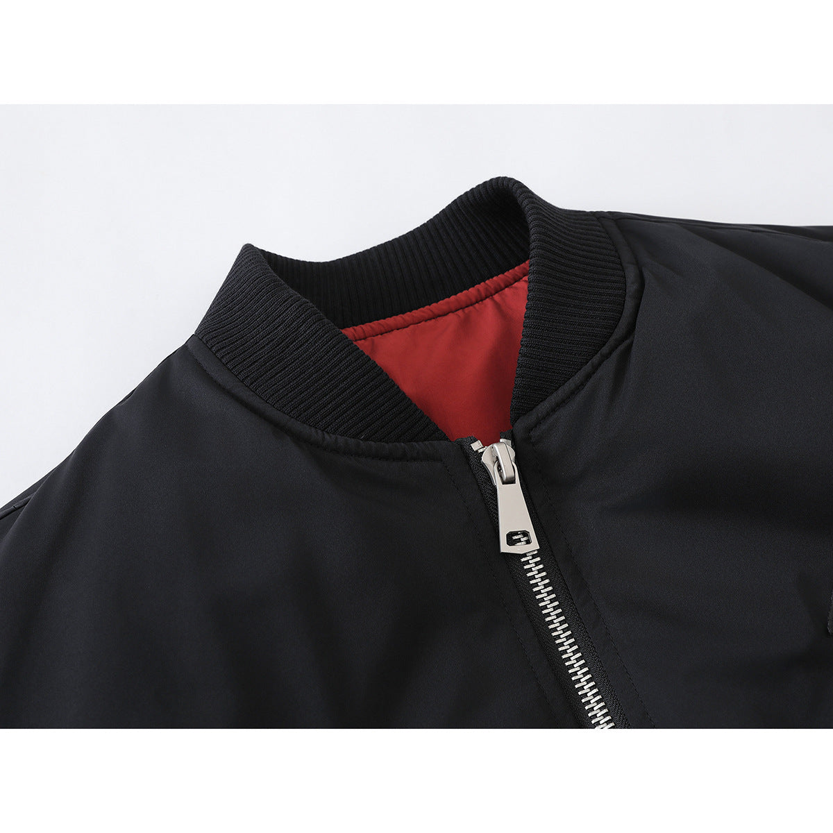 Close-up of a black jacket's ribbed collar, red lining, and silver front zipper.