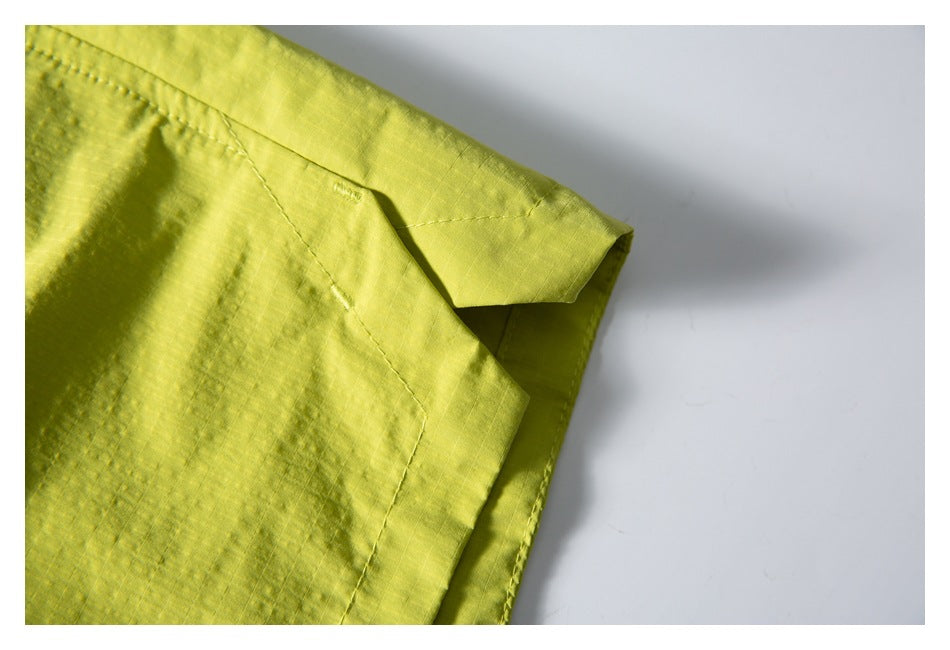 Close-up of a stitched pocket corner and folded edge on lime-yellow shorts.