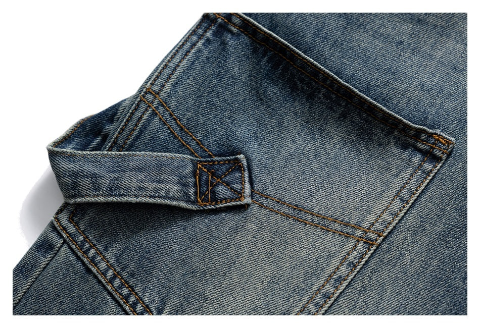 Close-up of blue-wash jeans showing a belt loop and intersecting seams across the rear waistband area.