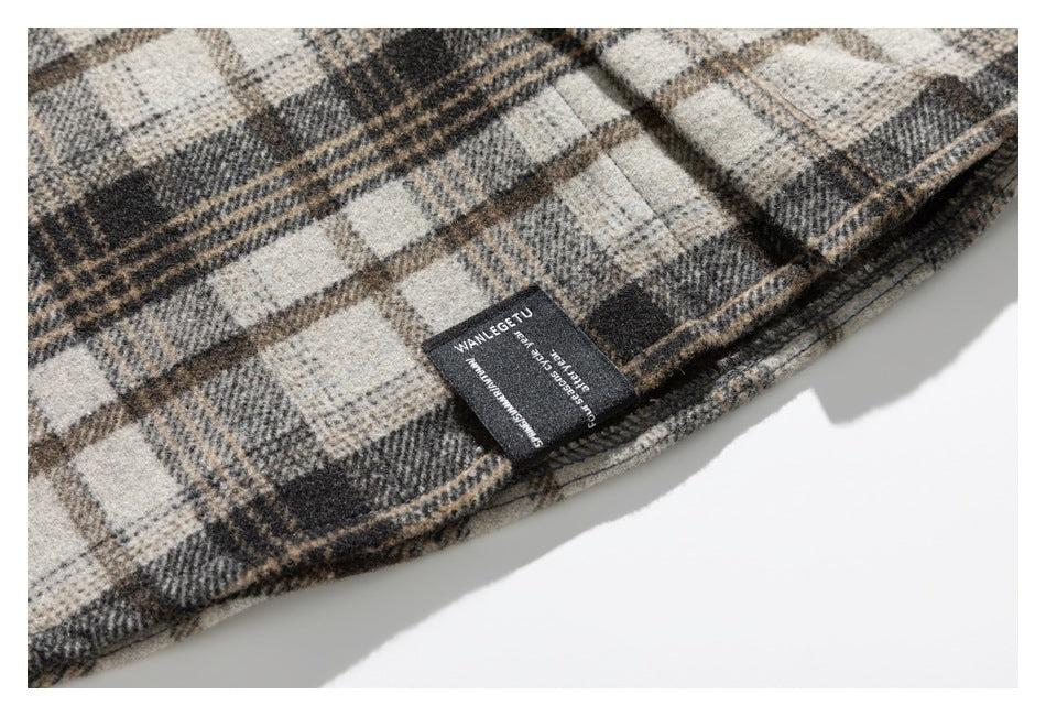 Close-up of the plaid garment’s hem with a small black sewn-in label bearing white lettering.