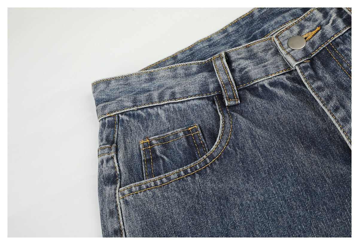 Close-up of the front pocket, coin pocket, belt loop and button on blue acid-wash jeans.