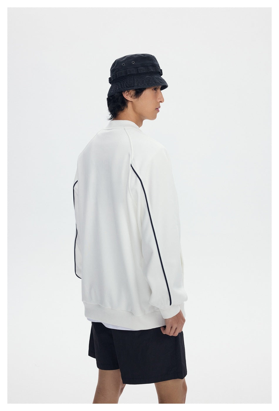Model shown from the back wearing a white sweatshirt with navy piping and black shorts.