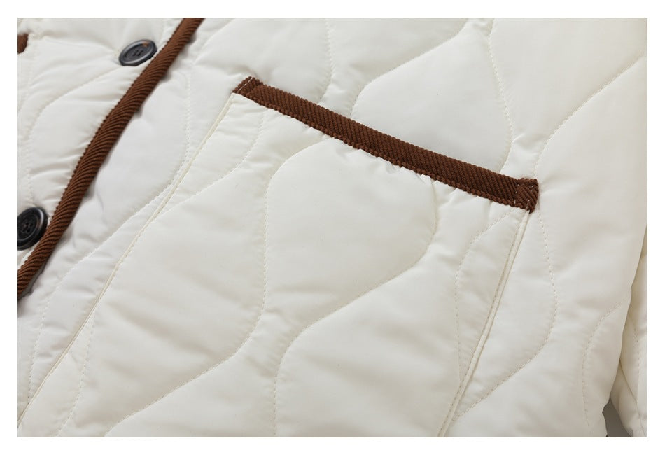 Close-up of a front pocket with brown corduroy edging on the ivory quilted jacket.