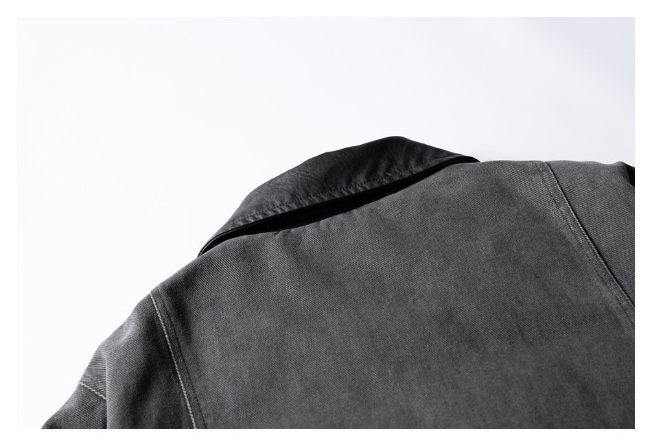 Close-up of a charcoal jacket collar and shoulder seam against a white background.
