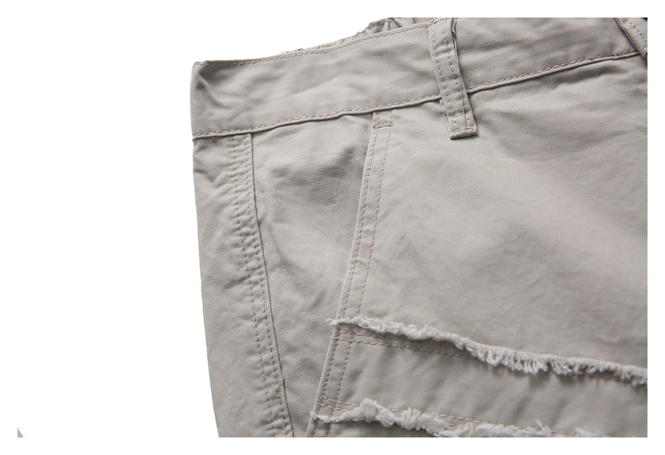 Close-up of a light taupe trouser pocket and waistband with a belt loop and frayed panel edge.