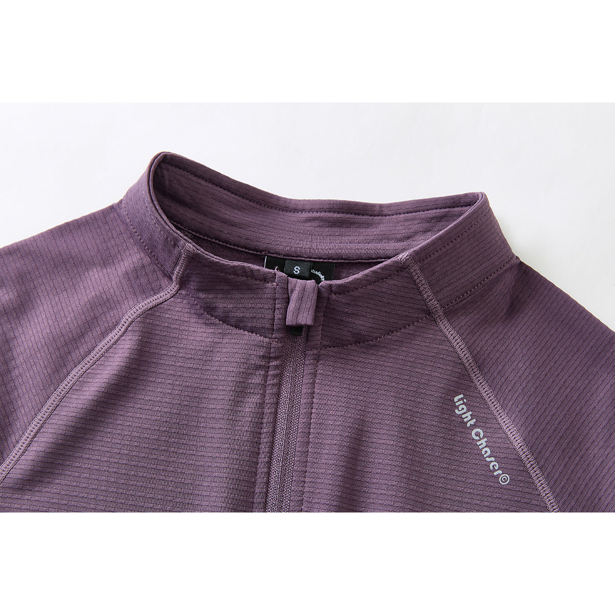 Close-up of a purple zip-up jacket's stand collar, zipper, and chest lettering.