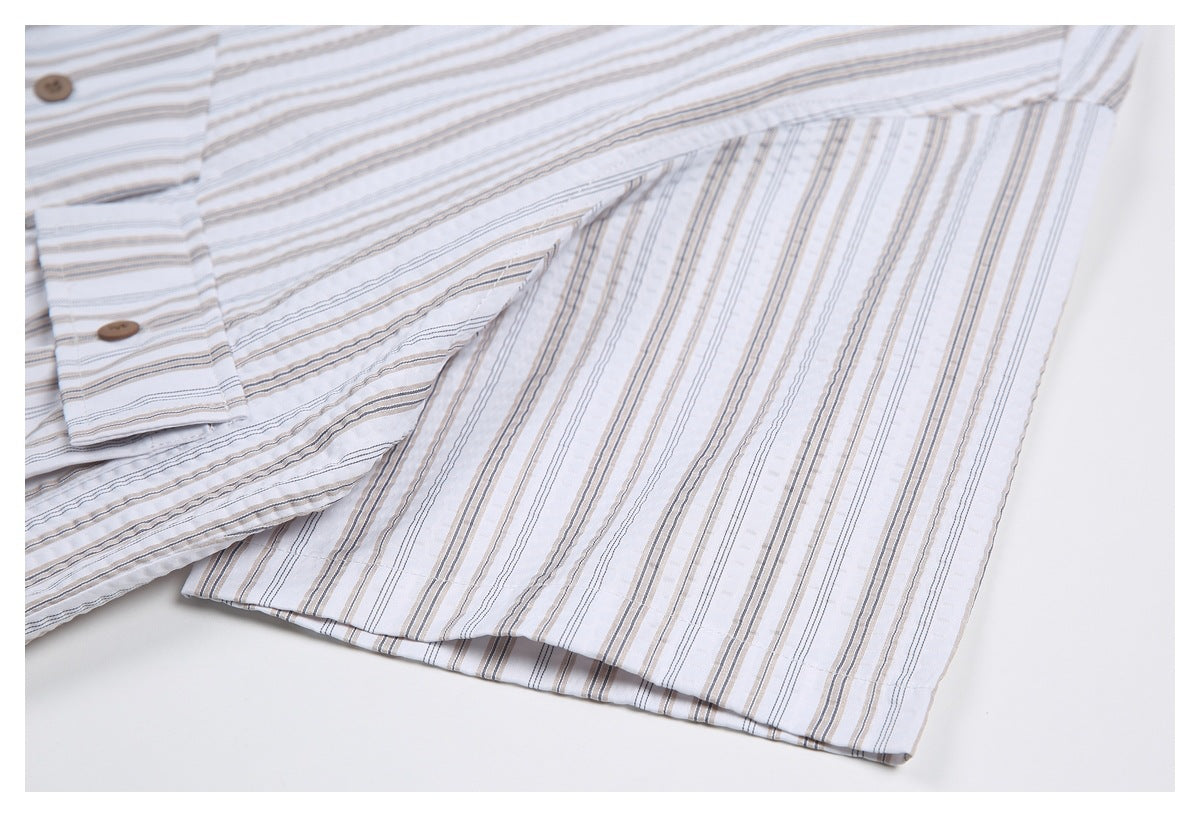 Close-up of a white striped button-up shirt showing the sleeve edge and brown buttons on the placket.