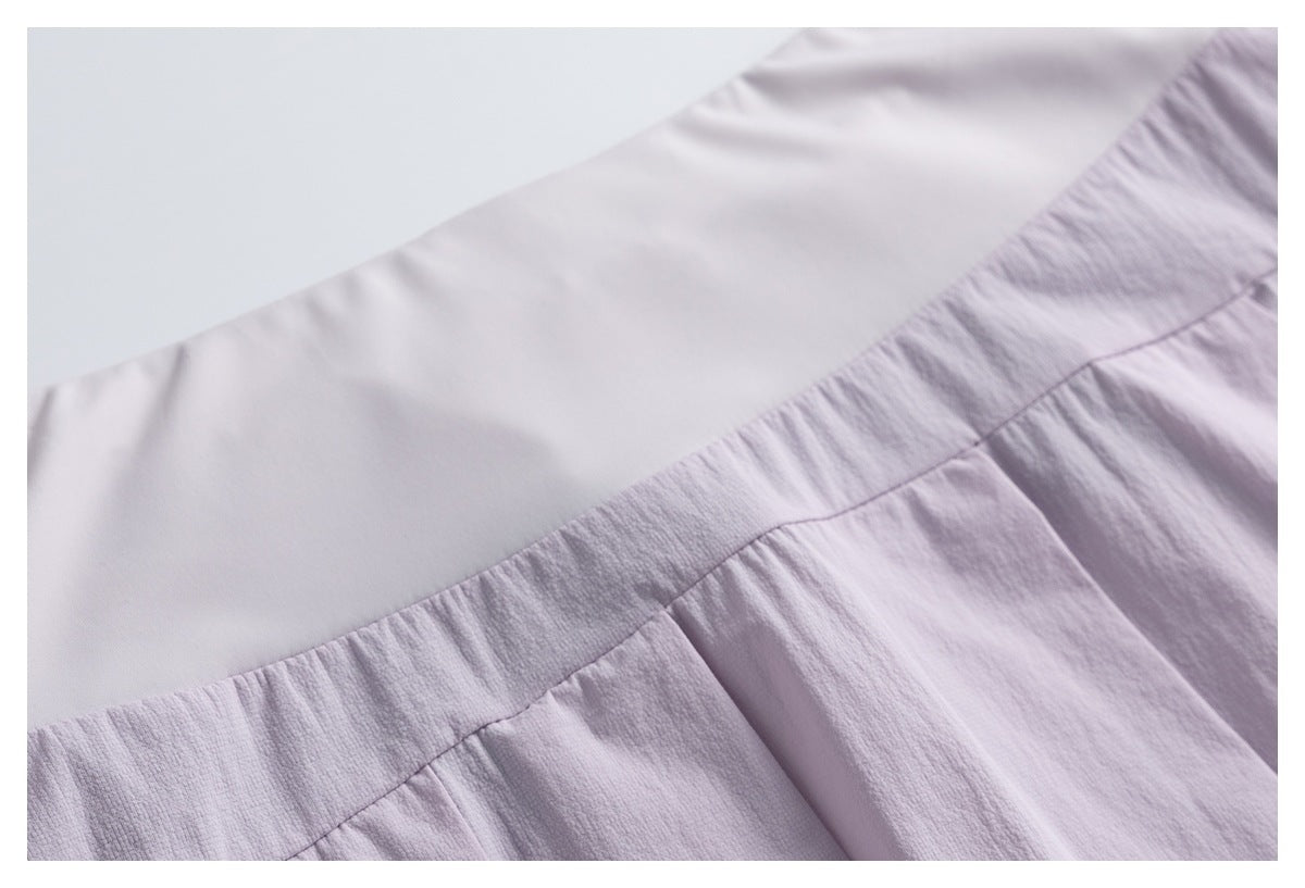 Close-up of a pale lavender garment with a smooth panel joined to gathered fabric at a curved seam.