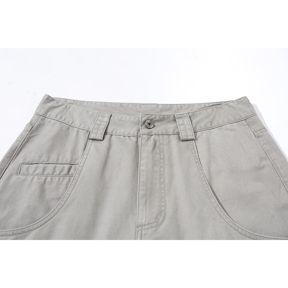 Close-up of light gray wide-leg trousers showing the waistband, button, belt loops and curved front pockets.