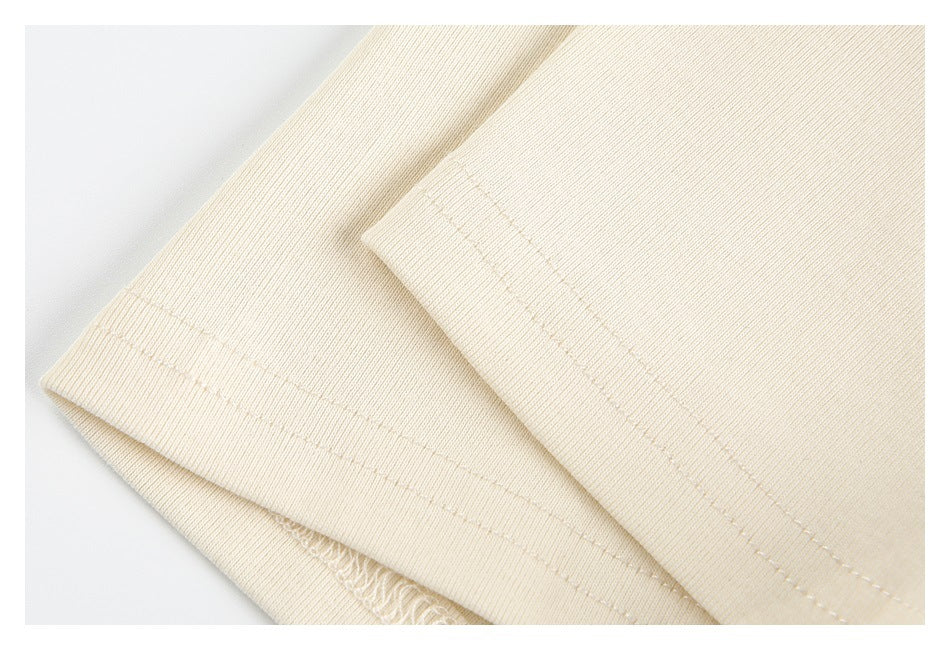 Close-up of folded cream garment edges showing parallel rows of stitching and an overlocked seam.