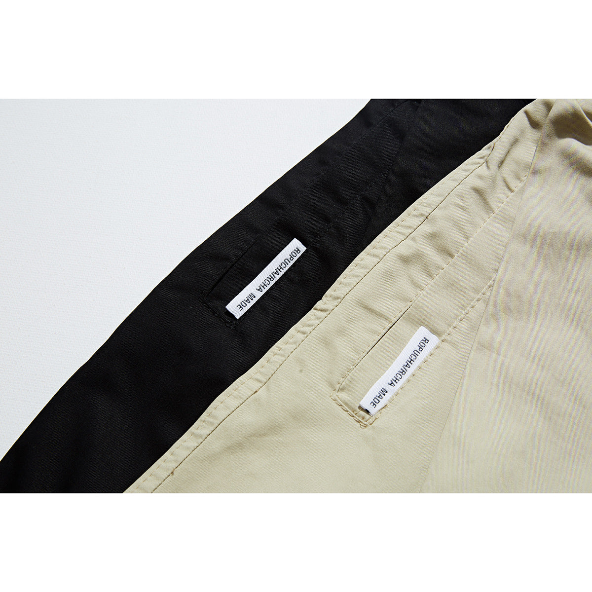 Close-up of sewn labels on black and beige shorts.