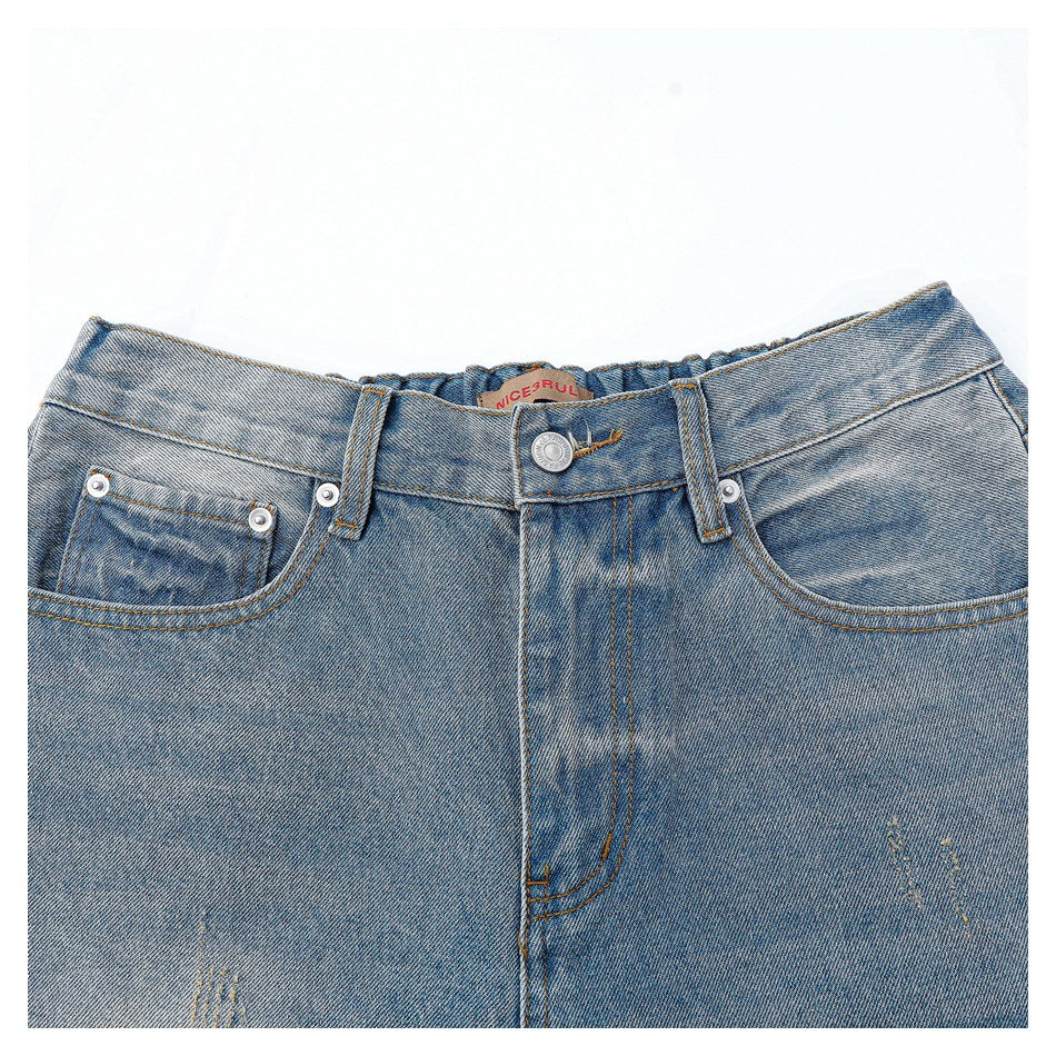 Close-up of blue faded jeans showing the waistband, button, belt loops, front pockets and inner label.