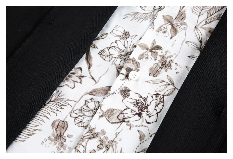 Close-up of a white shirt with brown floral print and white buttons beneath a black jacket.