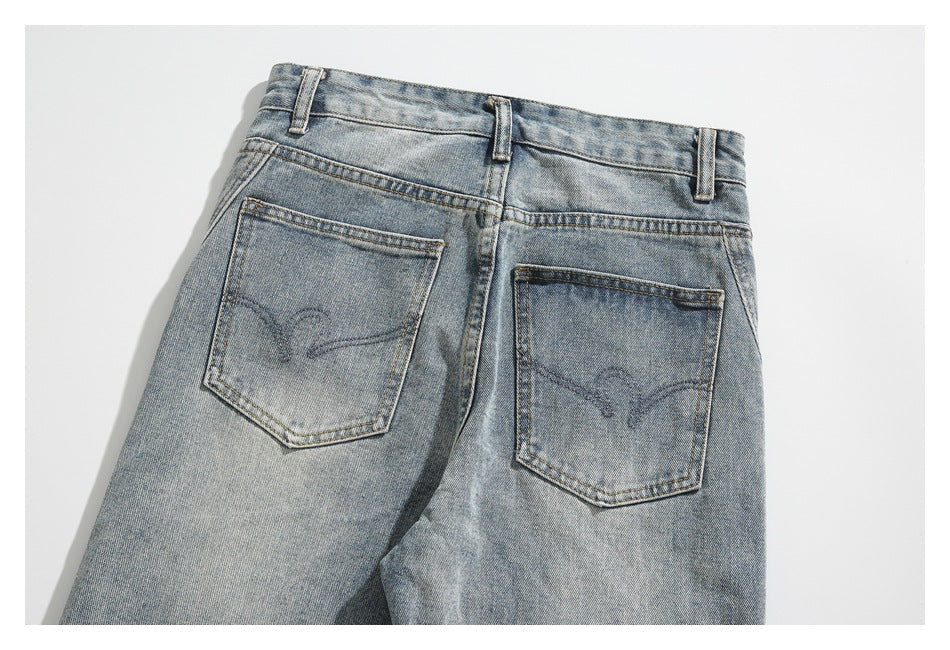 Cropped back view of light-wash jeans with belt loops and two stitched back pockets.