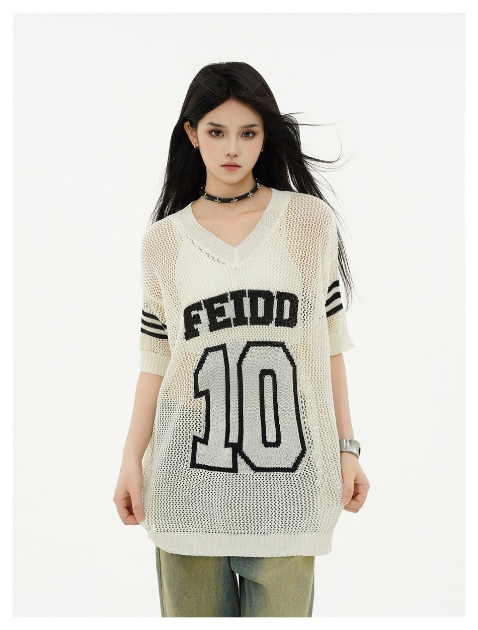 Model wearing an ivory mesh V-neck tunic with black sleeve stripes and FEIDD 10 lettering, shown with jeans.