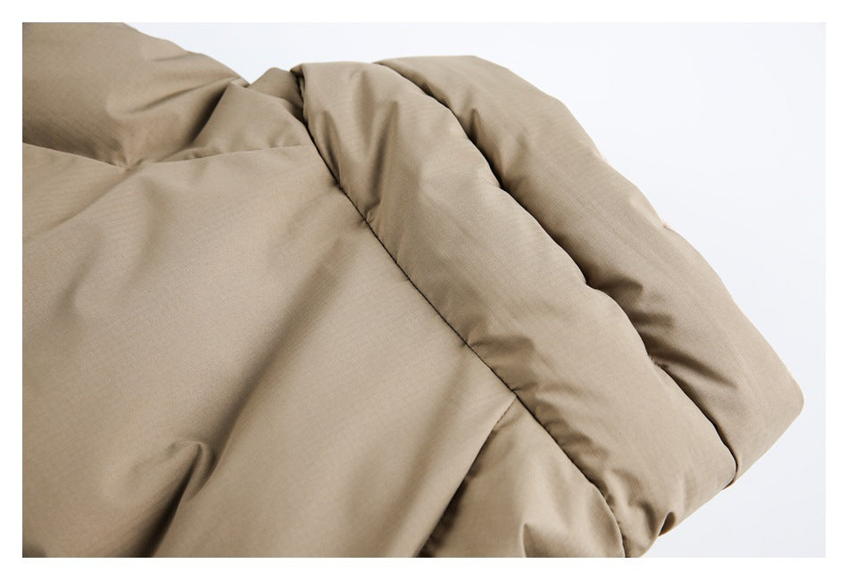 Close-up of tan garment fabric with a thick padded-looking folded edge and seam.