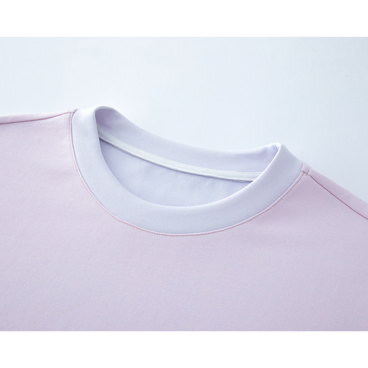 Close-up of a pale pink T-shirt with a white ribbed crew neckline.
