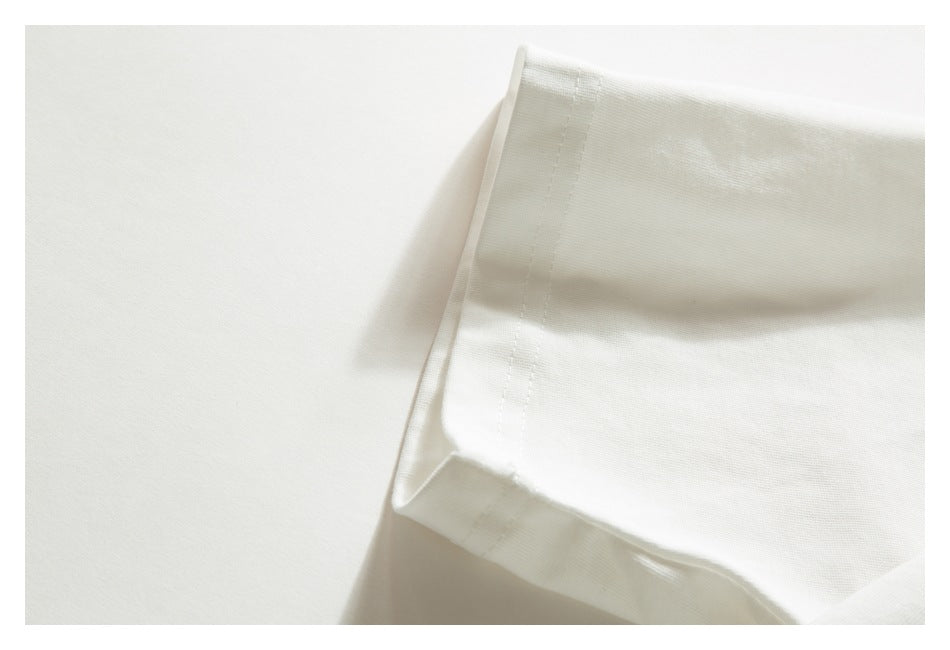 Close-up of a folded edge on white garment fabric with a narrow stitched seam.