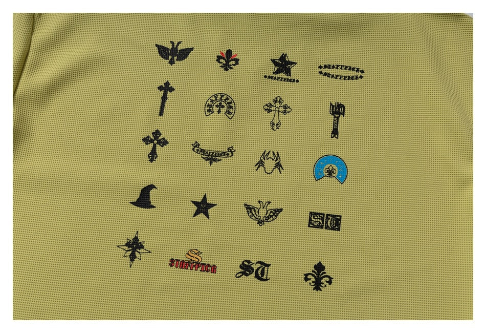 Close-up of assorted black and colored emblem graphics printed across olive-yellow perforated knit fabric.
