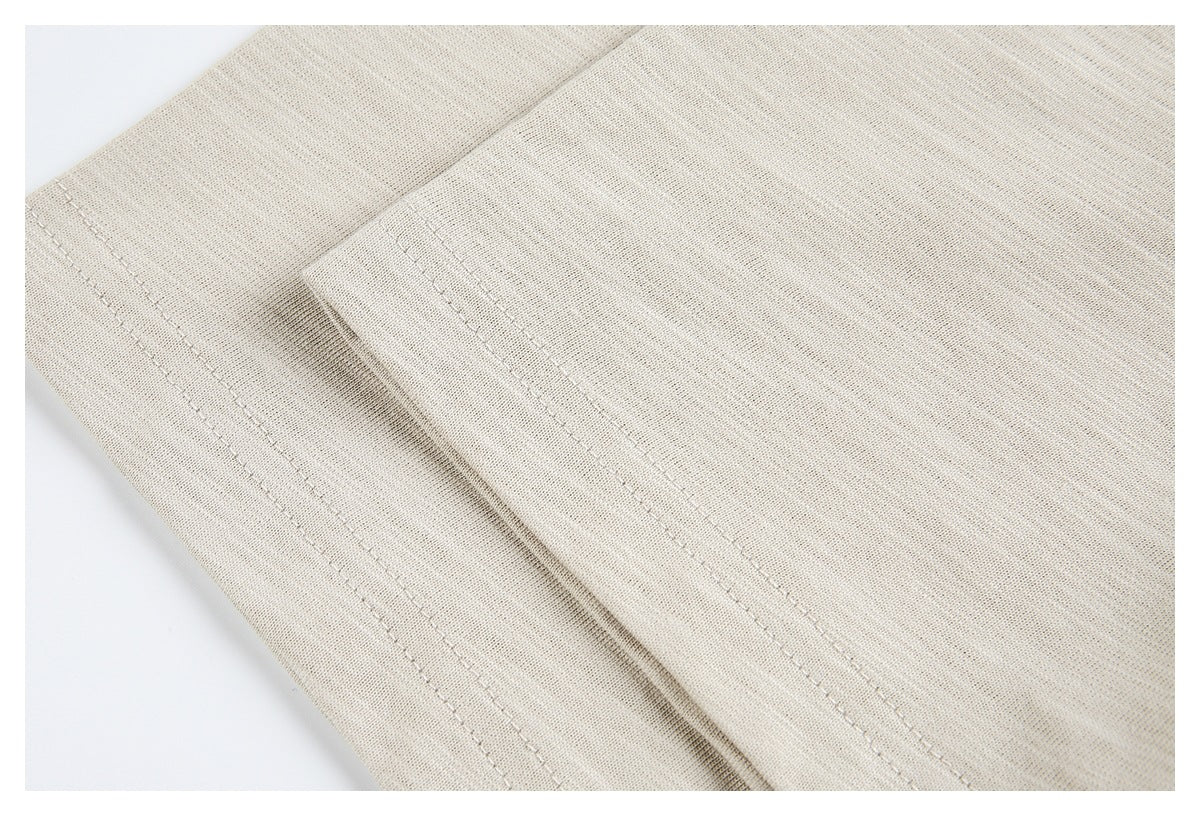 Close-up of a stitched edge on beige heathered garment fabric.