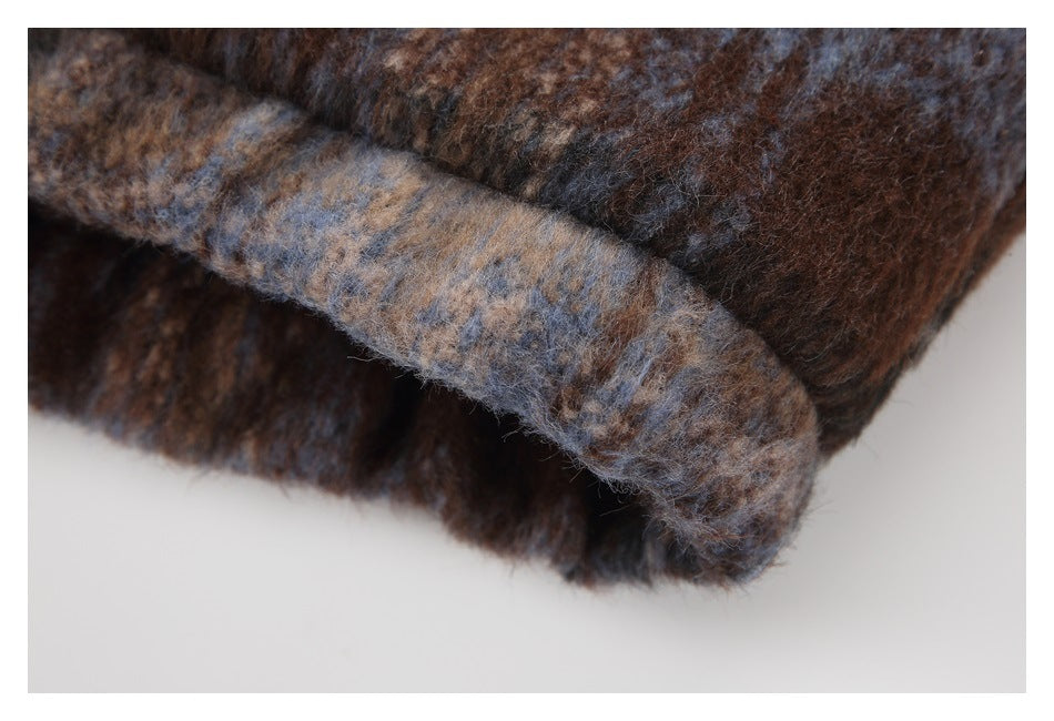 Close-up of a folded edge in the fuzzy brown-and-blue plaid jacket fabric.