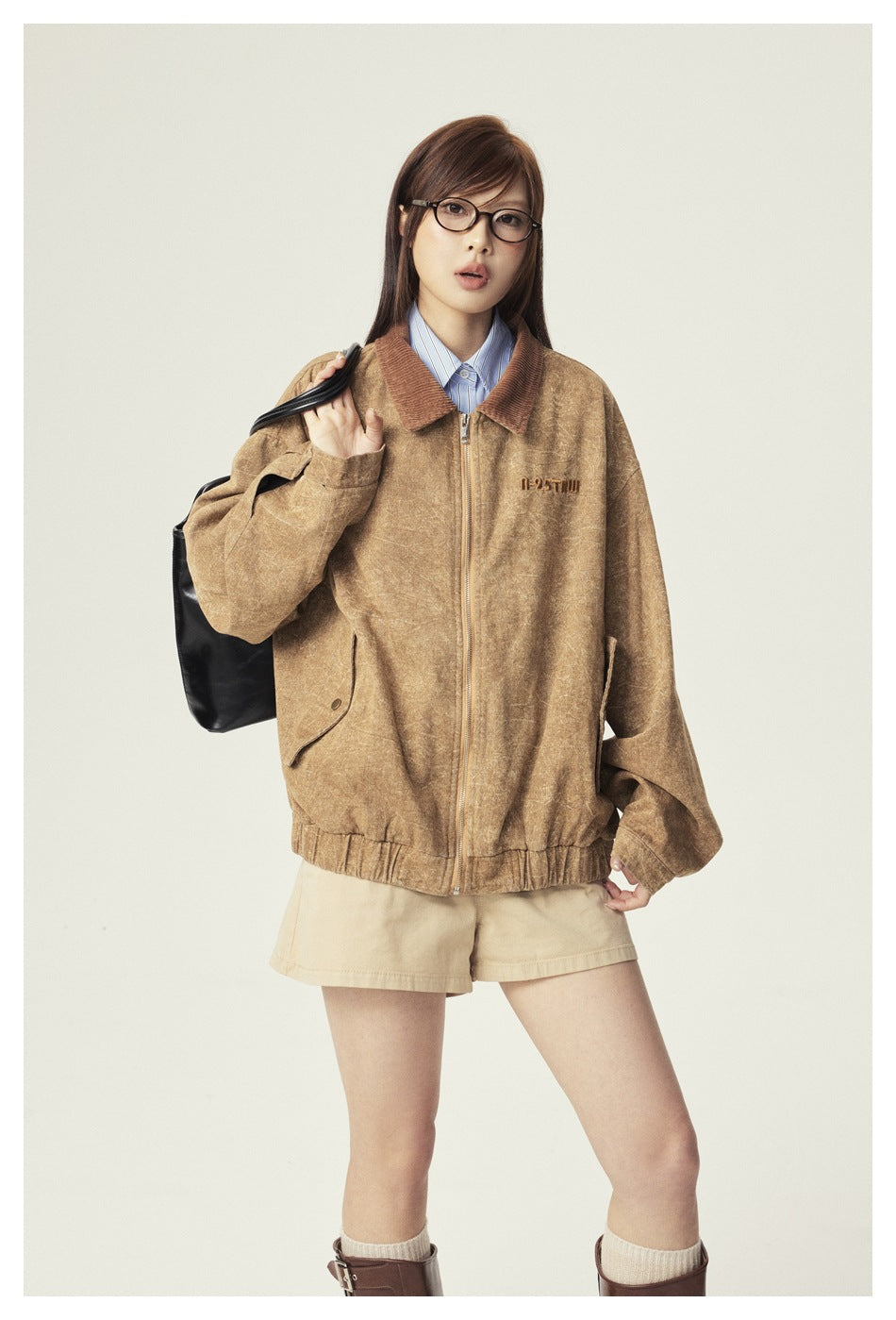Model wearing the khaki washed zip jacket over a striped shirt with beige shorts, holding a black tote bag