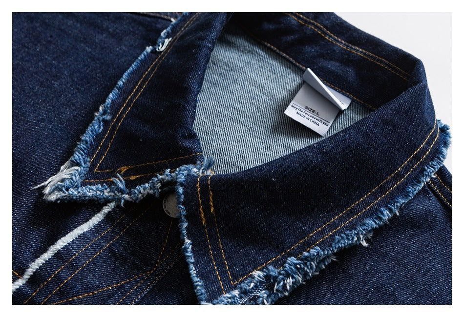 Close-up of a dark indigo denim collar with frayed edges, orange stitching, and a small size label.