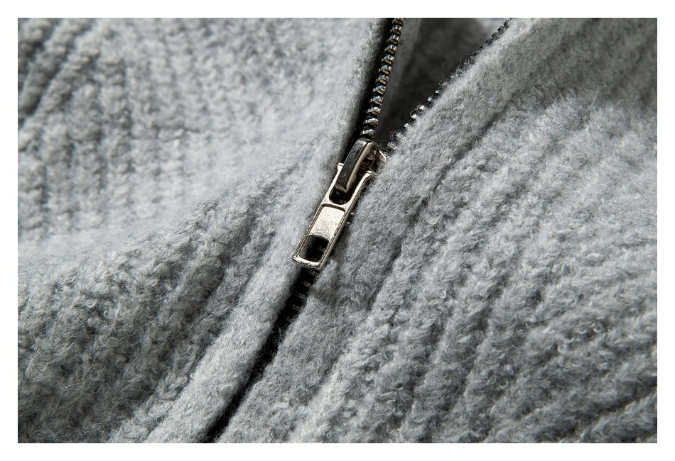 Close-up of a metal zipper on a light gray textured knit garment.