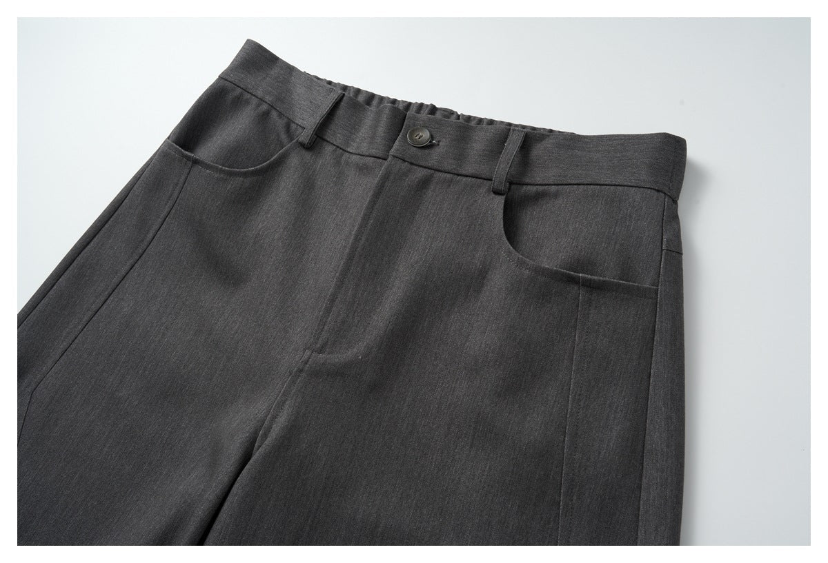 Front view close-up of charcoal gray trousers with a buttoned waistband, belt loops, and curved pockets.
