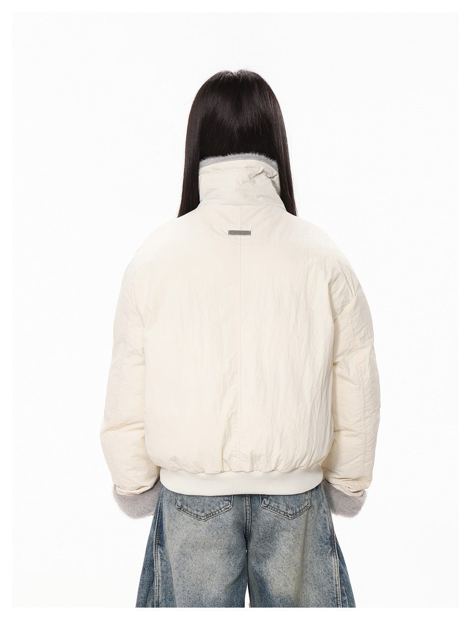 Back view of a model wearing an ivory jacket with a high collar, ribbed hem, and gray fur cuffs.