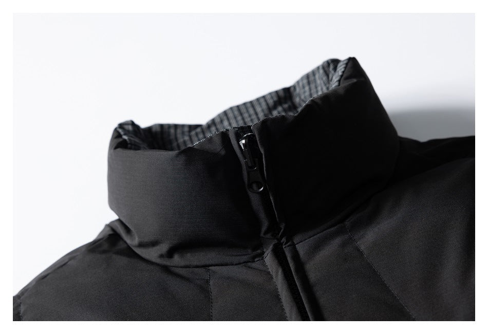 Close-up of a black jacket's raised collar, zipper, and checked inner lining.