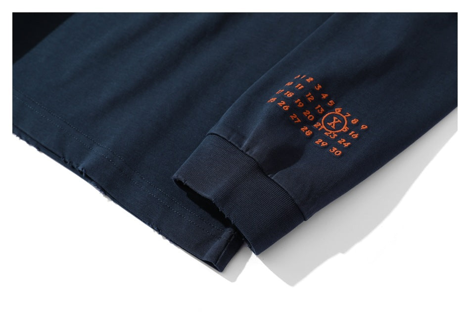 Close-up of a dark navy sleeve cuff with a small orange embroidered numbered design.