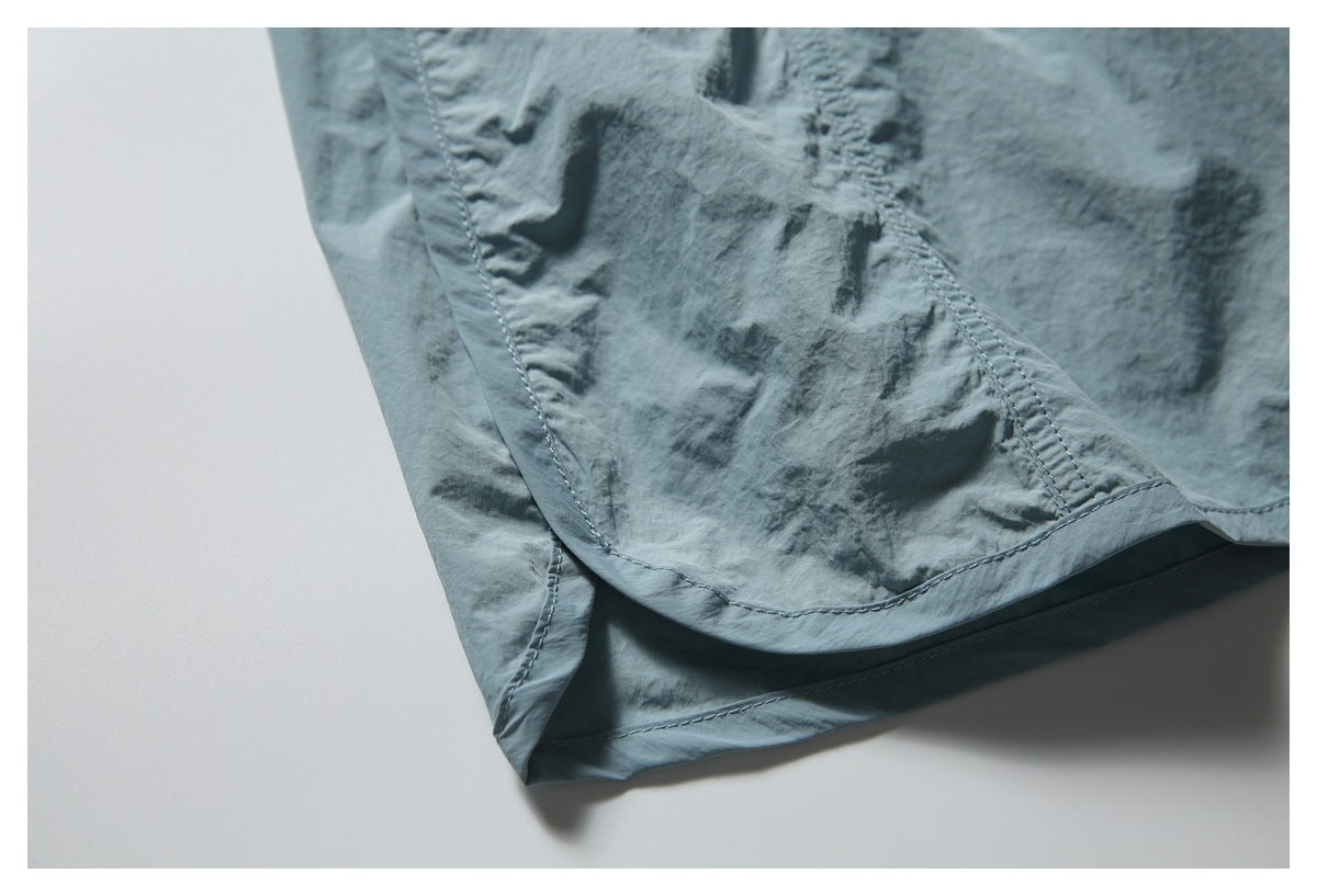 Close-up of the blue-gray shorts' stitched hem and overlapping lower fabric panels.