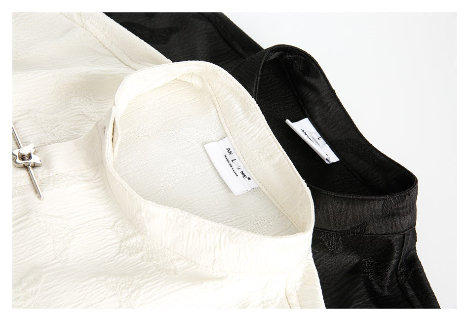 Close-up of ivory and black shirt collars, showing the textured fabric and sewn-in neck labels.