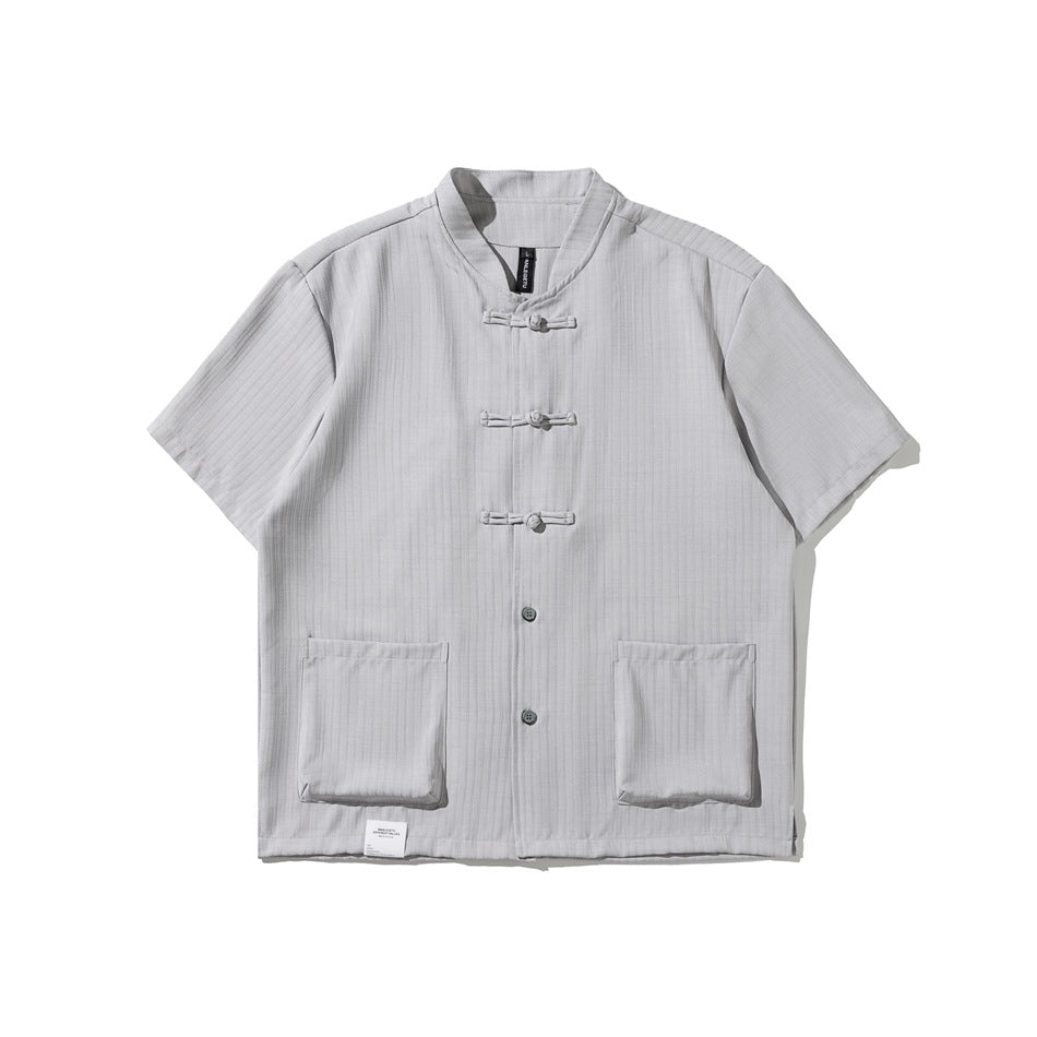 Light gray short-sleeve shirt with stand collar, knotted frog closures, buttons and two patch pockets, flat lay
