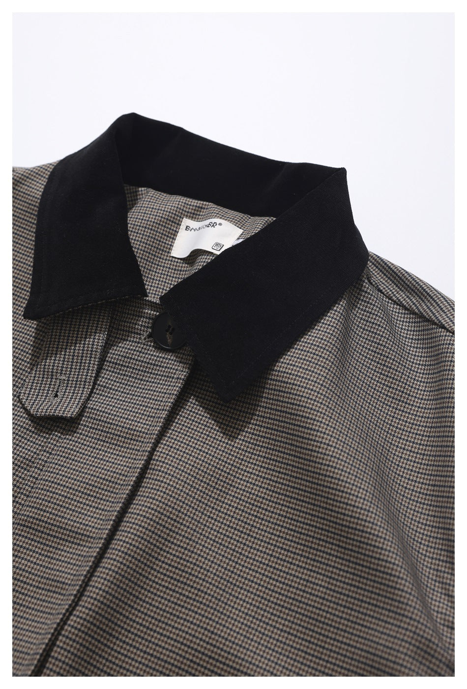 Close-up of a brown and black houndstooth jacket with a wide black collar and front button.