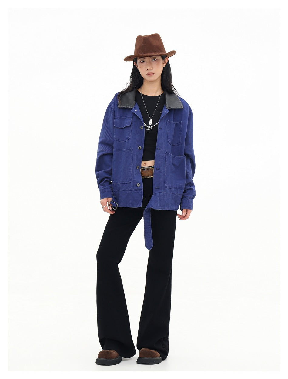 Full-length model wearing an open cobalt-blue utility jacket with a black collar and belt, black flared trousers and a brown