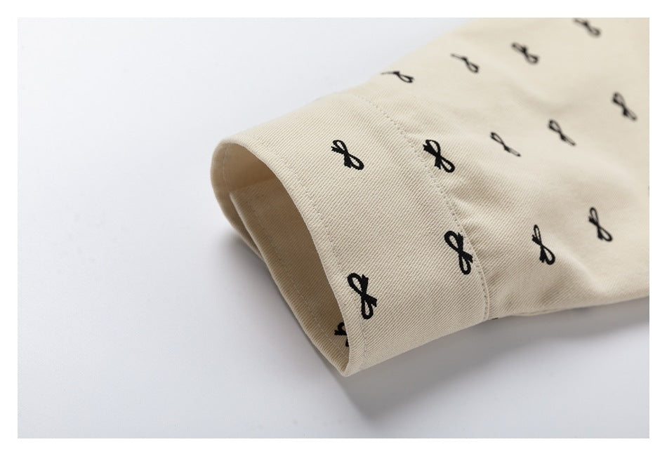 Close-up of a cream jacket sleeve cuff with visible stitching and small black bow motifs.