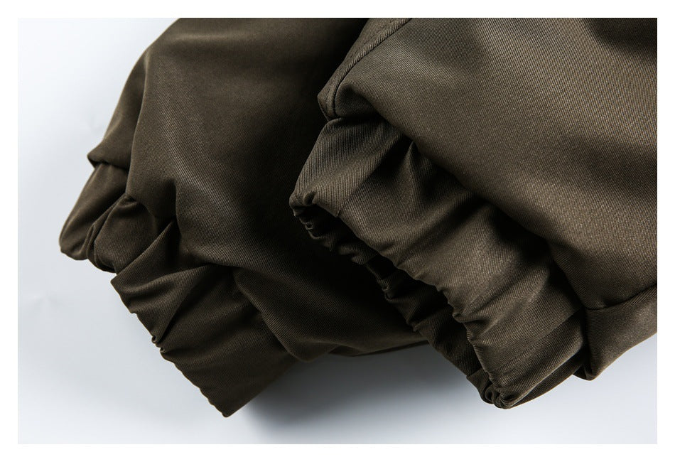 Close-up of gathered and folded olive-brown garment fabric with a stitched elastic edge.