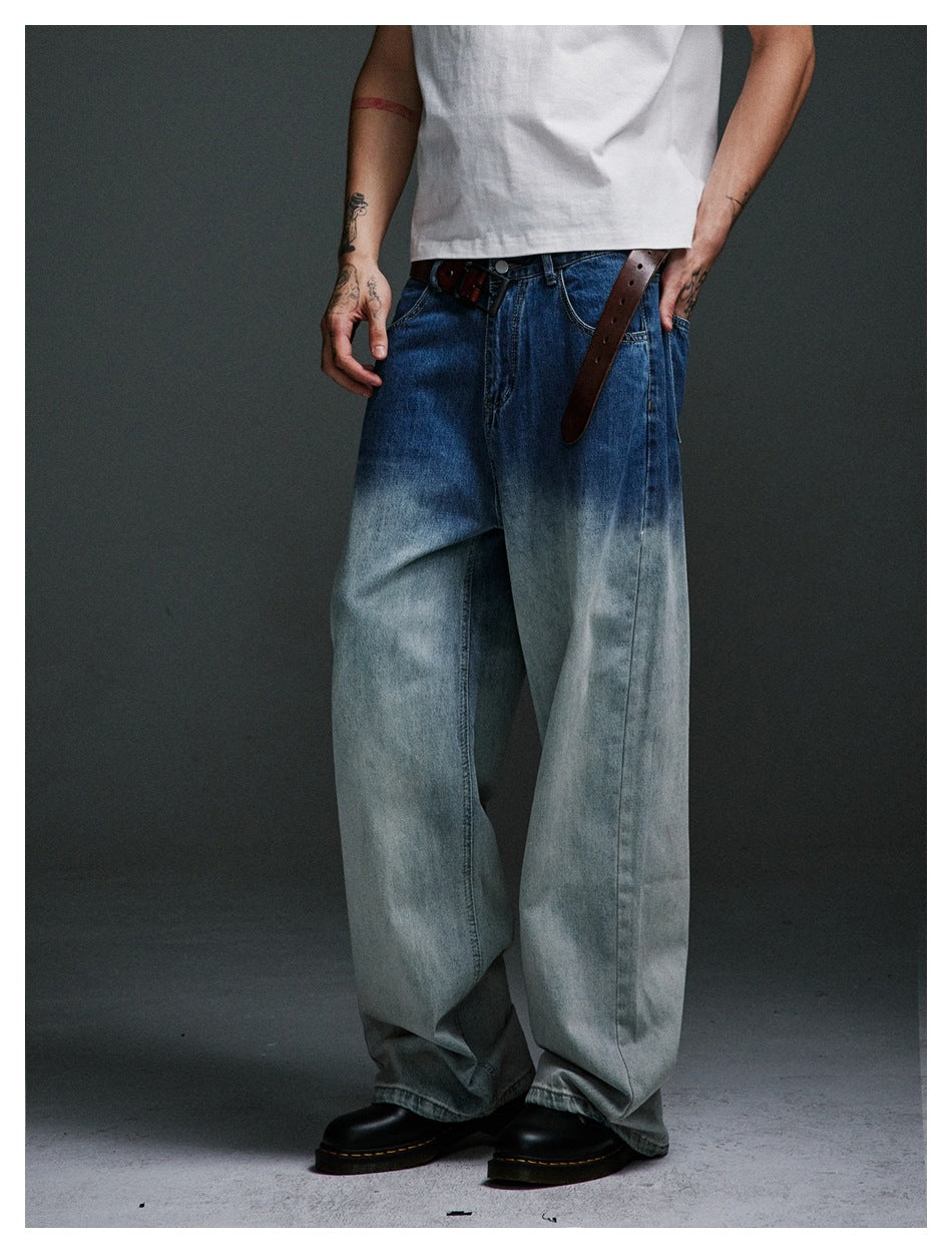 Person wearing blue-to-pale gradient wide-leg jeans with a brown belt, white tee and black boots, cropped at torso